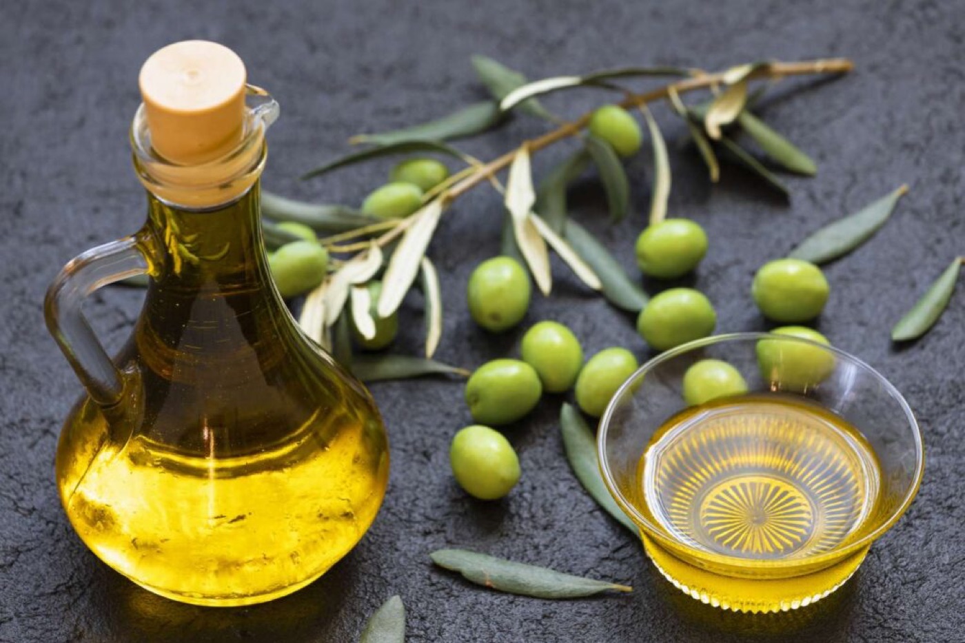 Bottle and bowl of extra virgin olive oil with fresh olives