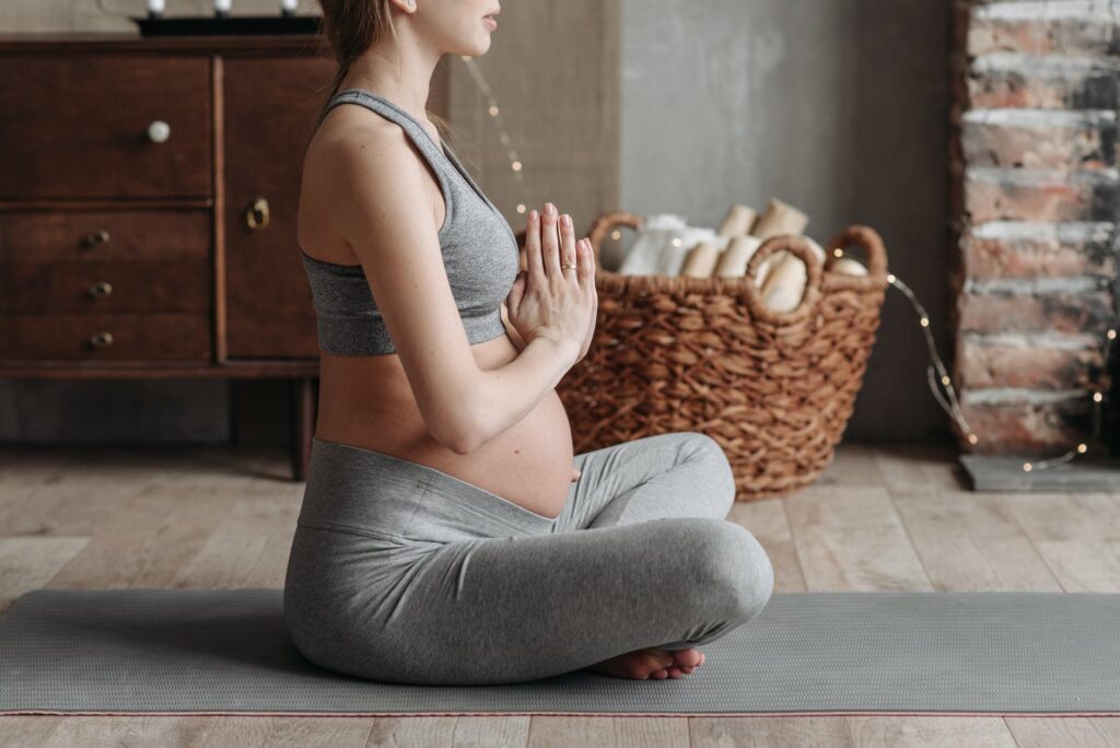 a pregnant woman wearing gray tank top meditating